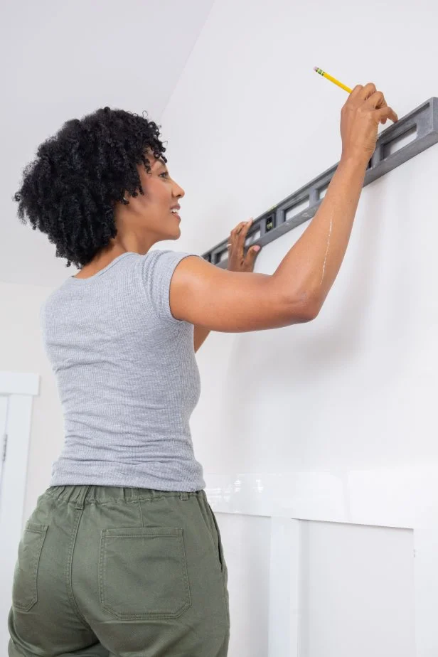 The next step in this DIY accent wall project is to draw the paint lines on the wall using a pencil and a level to ensure they're straight.